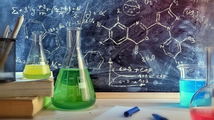 Classroom desk and drawn blackboard of chemistry teaching with books and instruments. Chemical sciences education concept. Horizontal composition. Front view