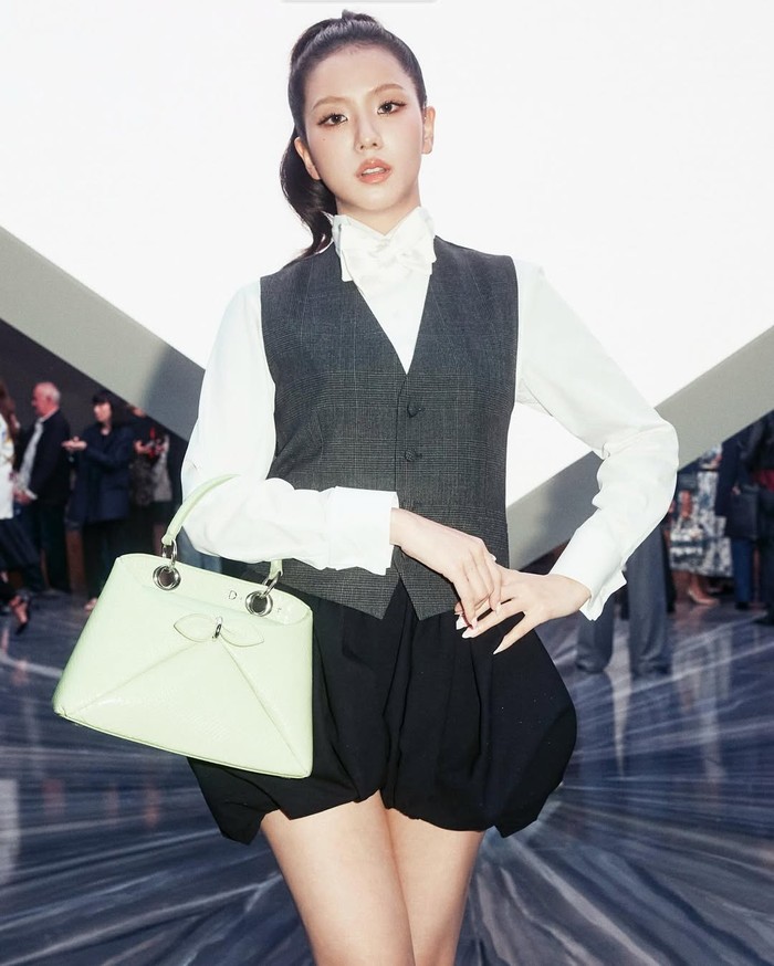 Kemeja putih ber-pita, waistcoat abu-abu, mini skirt hitam puffball, heels peep-toe, dan tas hijau pastel jadi pilihan Jisoo Blackpink saat hadiri fashion show Dior/Foto: instagram.com/sooyaaa__