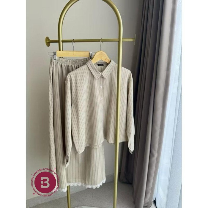 Warnanya netral, yakni beige, dengan motif garis ramping. Aksen renda pada rok menambah kesan manis pada one set ini.