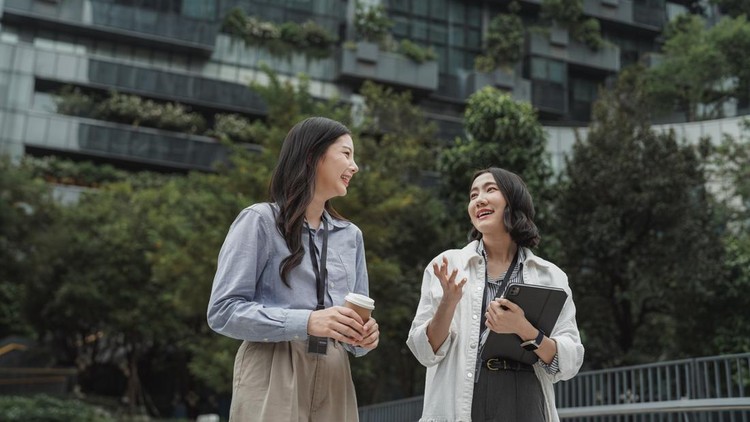 Ilustasi pekerja kantor Two woman colleagues enjoying their break in the park, discussing ways to promote sustainability in the workplace