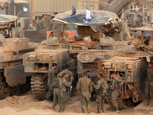 Israeli army soldiers gather near infantry-fighting vehicles (IFVs) at a position along the Israel-Gaza border fence on October 10, 2025. Gaza's civil defence agency said October 10 that Israeli forces have begun pulling back from parts of the territ