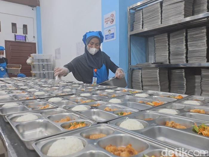 Relawan SPPG Prabumulih menempatkan lauk pauk di ompreng saji dalam ruang pemorsian dapur MBG. ruang khusus