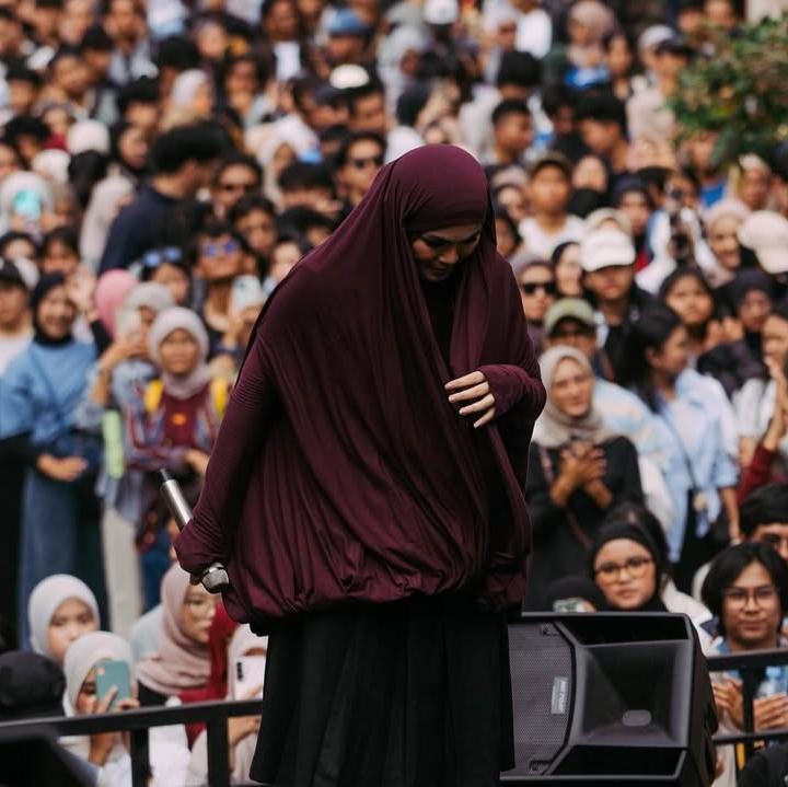<p>Perempuan 28 tahun ini menarik perhatian lewat <em>outfit</em> yang dipakainya. Ia terlihat mengenakan busana muslim dengan hijab syari berwarna merah maroon dan rok berwarna hitam.&nbsp;(Foto: Instagram@siviazizah)</p>