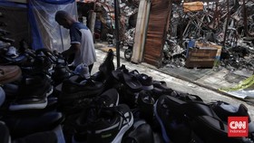 Warga melintasi puing bangunan dan lapak yang hangus terbakar di Pasar Taman Puring, Jakarta, Kamis, 23 Oktober 2025. (CNN Indonesia/Adhi Wicaksono)