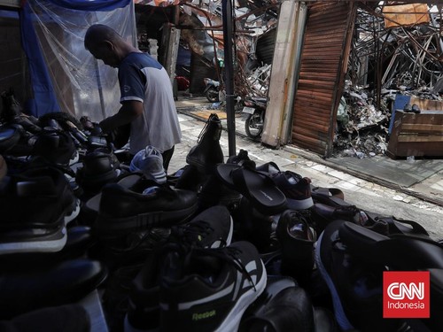 Warga melintasi puing bangunan dan lapak yang hangus terbakar di Pasar Taman Puring, Jakarta, Kamis, 23 Oktober 2025. (CNN Indonesia/Adhi Wicaksono)