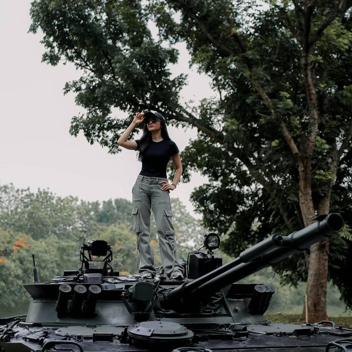 <p>Melalui unggahan di Instagram, Febby juga membagikan potret saat ia berpose di atas mobil tank hitam. Perempuan kelahiran Jakarta ini memamerkan gayanya yang keren saat di atas mobil tank sambil mengenakan kaus hitam dengan celana <em>cargo jeans</em> dan topi. (Foto: Instagram @febbyrastanty)</p>