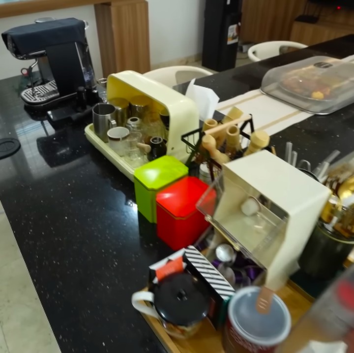 <p>Memasuki area rumah, Bunda akan melihat dapur di dekat pintu masuk. Dapur besar ini direnovasi dengan dominasi warna minimalis, seperti hitam dan cokelat. Di salah satu meja dapur, perempuan yang akrab disapa Acha ini meletakkan peralatan untuk membuat kopi hingga matcha. Bunda tiga anak ini memang dikenal suka dengan minuman kopi serta matcha. "Jadi Acha tuh suka bikin matcha dan kopi sendiri di rumah. Bikin matcha atau kopi itu kaya rutinitas atau kebiasaan yang menjadi <em>me time</em> buat aku," katanya. (Foto: YouTube TAULANY TV)</p>