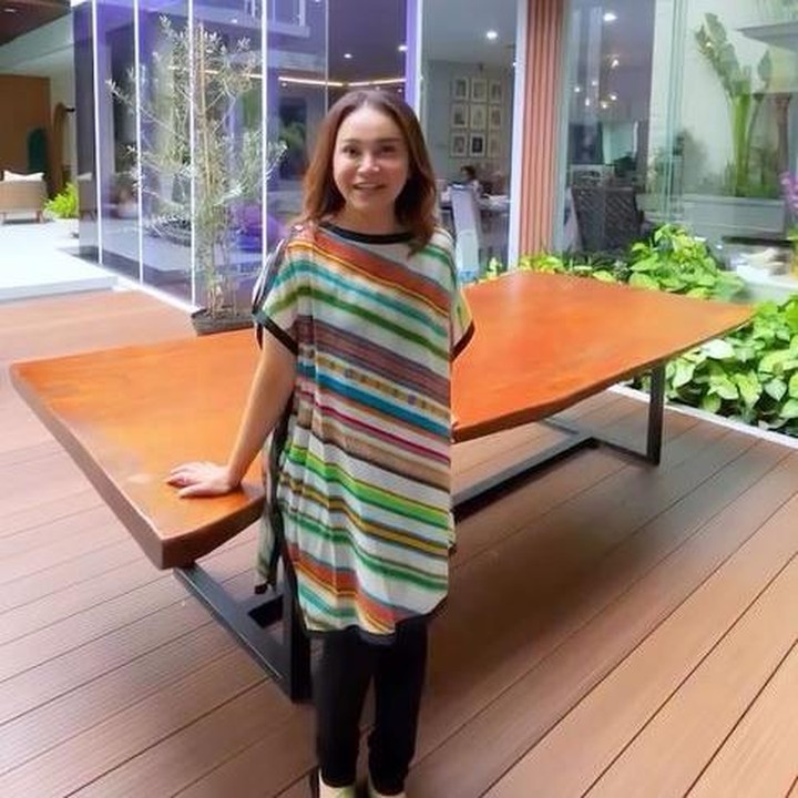 <p>Di sudut dekat kolam, Rossa meletakkan meja kayu besar. Meja ini sering digunakan Rossa untuk menjamu teman-temannya saat berkunjung ke rumah. "Meja ini adalah meja makan yang biasanya kalau aku lagi menjamu teman-teman aku, pas <em>dinner</em> atau makan di luar, aku pakai meja ini," katanya. (Foto: Instagram @itsrossa910)</p>