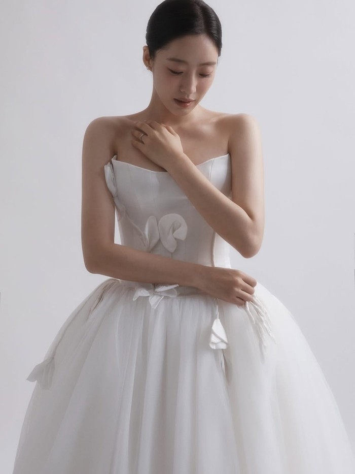 Keanggunan memancar kuat dalam penampilan Eunjung yang mengenakan gaun pengantin putih dengan aksen-aksen bunga. Dominasi warna putih pada foto seolah menyiratkan bersihnya lembaran baru yang diawali dengan kesucian./ Foto: instagram.com/eunjung.hahm