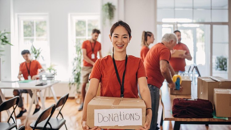 Portrait of volunteer holding donation box with goods for people in need