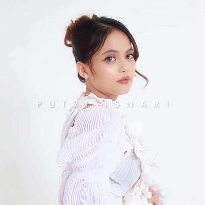 <p>Dalam <em>maternity shoot</em> ini, Putri terlihat mengenakan gaun berwarna putih dengan makeup looks yang simpel namun membawa kesan warm. Penampilannya semakin anggun dengan model rambut diikat cepol tinggi dan poni panjang yang dibiarkan jatuh di samping wajah. (Foto: Instagran @putriisnari3)</p>