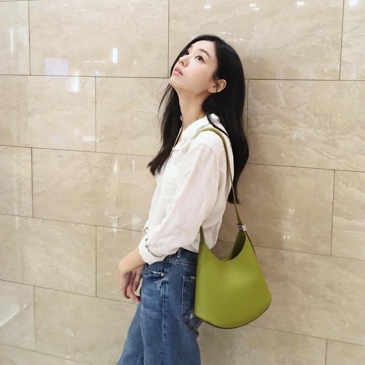 <p>Misalnya saja, seperti foto berikut ini. Ia tampil santai menggunakan celana jeans yang dipadu padan dengan kemeja putih. Penampilannya dilengkapi dengan warna tasnya yang cerah berwarna hijau.&nbsp;(Foto: Instagram @eunjin__a)</p>