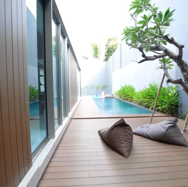 <p>Di area belakang rumah, Mona dan Indra membangun kolam renang yang panjang dengan nuansa mirip seperti vila di Bali. Di dekat kolam renang, pasangan ini membuat ruang santai yang dibangun di atas lantai kayu cokelat. Di ruangan ini, keduanya meletakkan sofa big bean dan kolam kecil berisi pasir untuk tempat bermain anak mereka yang masih kecil. Suasana di sini mirip dengan villa di Bali, Bunda. "Iya kayak vila di Bali. Di sini lebih privasi lah, karena kita memang bikin area sini itu lebih nyaman," ujar Indra. (Foto: YouTube AH)</p>