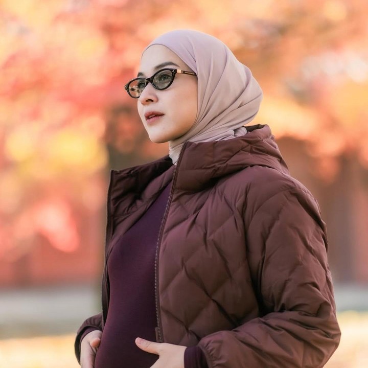 <p>Dalam maternity shoot ini, Nina mengenakan baju bernuansa warna cokelat dan <em>berry maroon</em>, mulai dari jaket hingga jilbab. Gayanya yang stylish ini begitu cocok dengan pemandangan dedaunan dari pepohonan musim gugur di kawasan Gyeongbokgung Palace, Korea Selatan. (Foto: Instagram @ninazatulini22)</p>