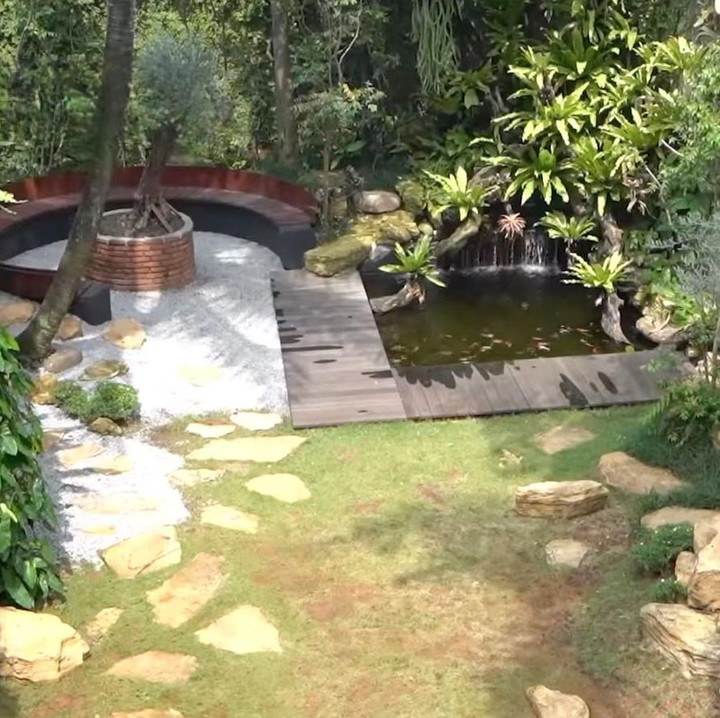 <p>Tidak hanya itu saja, di sebelah kursi bulat juga terdapat kolam ikan yang cukup besar. Irfan memang piawai menatanya, Bunda. Kolam tersebut tampak dikelilingi pepohonan yang membuat suasananya terasa lebih sejuk. (Foto: Youtube @deHakims)</p>
