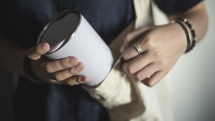 Young woman bringing and taking out tumbler, reusable coffee mug/cup from her bag.