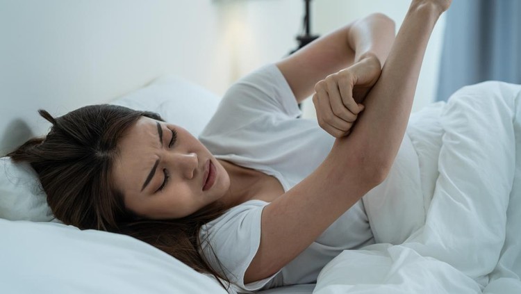 Asian young woman scratch hand feel suffer from allergy while sleeping. Beautiful attractive girl lying on bed in bedroom suffering from itching arm skin allergic reaction to insect bites, dermatitis.