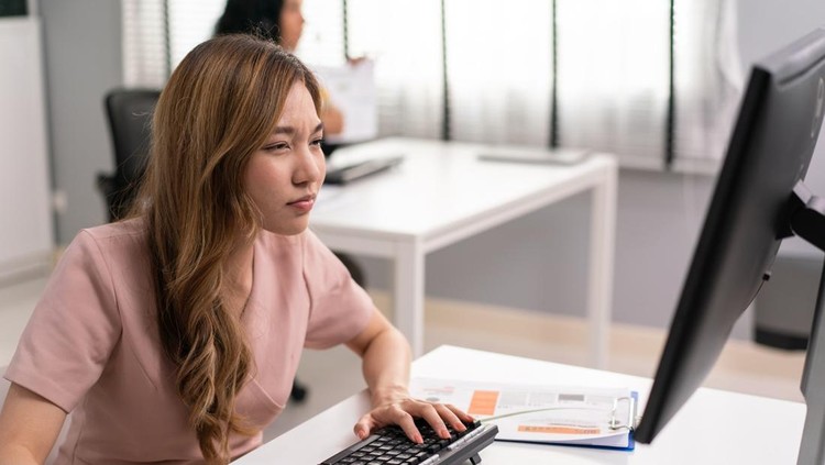 Asian female employee having farsighted problem looking at monitor, Blue light hazard from computer screen. woman tired of focusing on reading and working in the office.