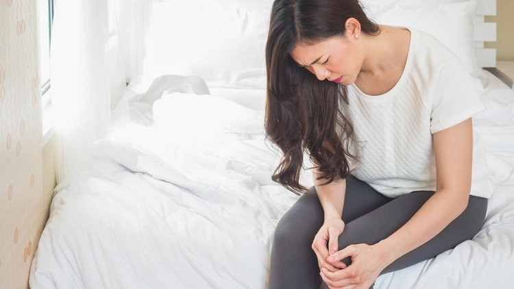 Asian woman holding knee in bed room, woman hurt pain at knee concept