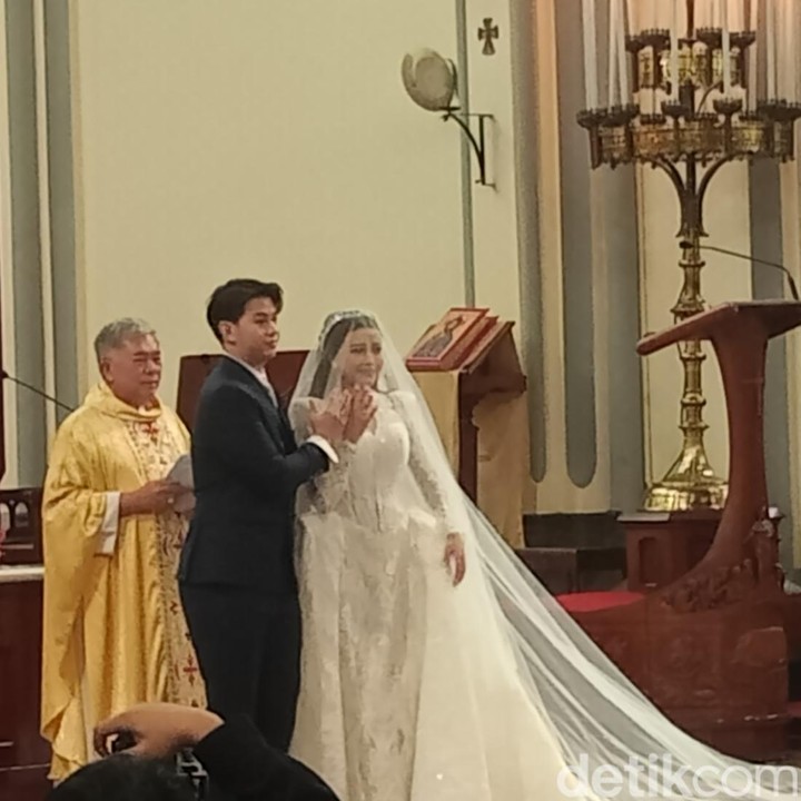 <p>Brisia nampak cantik mengenakan gaun bernuansa putih dengan potongan clean yang menonjolkan V-neck yang membuatnya nampak semakin anggun. Rambutnya dibiarkan tergerai berhias dengan tiara putih menghias mahkota kepalanya. Selamat menempuh hidup baru untuk Brisia dan Alden. (Foto: Muhammad Ahsan Nurrijal/detikcom)</p>