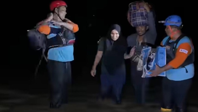 Wanita Aceh Tamiang pingsan karena kelelahan dan lapar setelah berjalan belasan kilometer di tengah banjir. Suami menggendong sebelum dibantu tim relawan mengevakuasi. Unggahan terseut langsung viral.