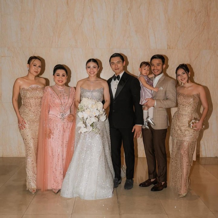 <p>Dalam unggahan itu, Jessica juga tampil kompak mengenakan baju dengan nuansa yang sama yaitu glamor. Jessica bersama ketiga kakak iparnya tampil elegan mengenakan gaun dengan sentuhan warna <em>gold,</em> sementara ibu mertuanya berwarna merah muda.&nbsp;(Foto: Instagram @jscmila)</p>