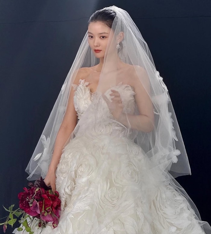 Kim Yoo Jung kembali berkesempatan mengenakan gaun pengantin di proyek drama. Gaun putih yang dilengkapi veil berbunga di atas merupakan gaun dengan tampilan paling mewah yang pernah dikenakan oleh sang aktris./ Foto: instagram.com/awesome_ent_official