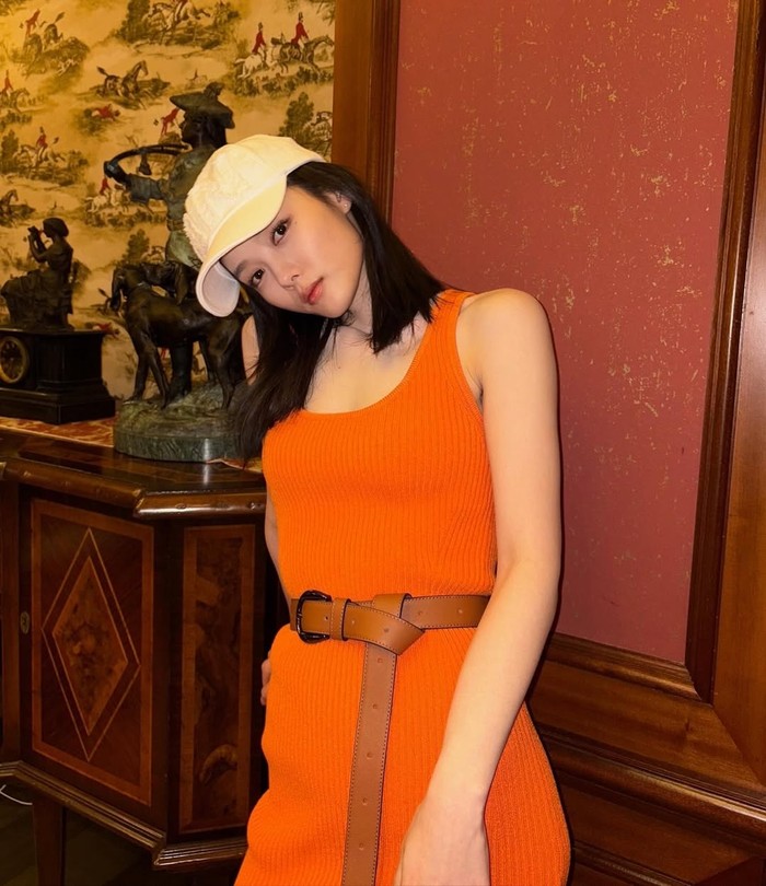 Penampilan glamour Kim Yoo Jung sebagai Baek Ah Jin juga mencakup menggunakan warna-warna terang yang menunjukkan rasa percaya diri sebagaimana dress bewarna oranye yang berpadu elegan dengan sabuk kulit dan topi./ Foto: instagram.com/awesome_ent_official