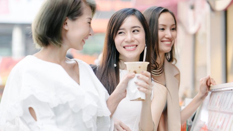 Young beautiful women shopping together, outdoors, smiling, buying refreshing drink