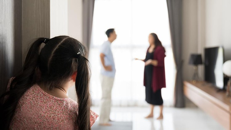 Back view of child girl crying at the door from father and mother arguing. Little girl crying because parents arguing blur background. family negative, quarrels concept.