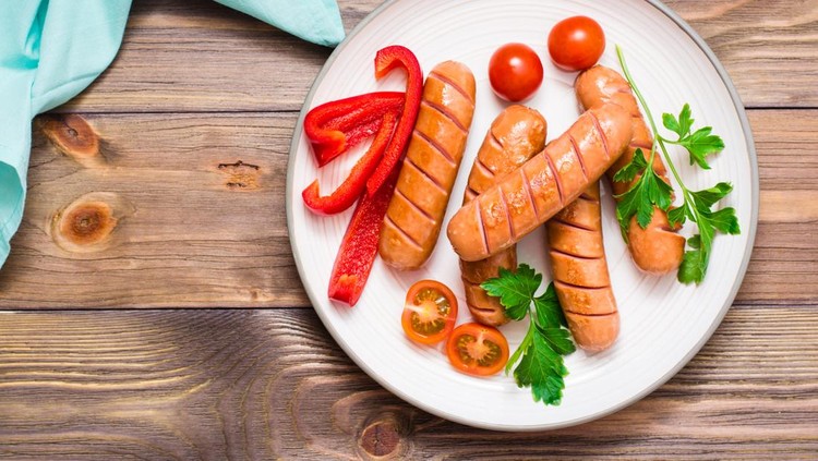 Grilled sausages&comma; fresh tomatoes&comma; peppers and parsley on a plate on a wooden table&period; Top view