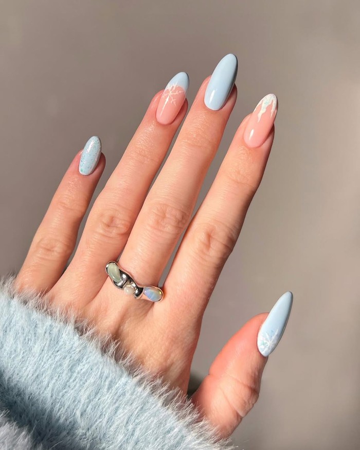 Frosty blue winter nail art menciptakan nuansa winter wonderland di kuku kamu. Kombinasi biru es dan detail putih berkilau memberi kesan dingin yang dreamy./ Foto: instagram.com/amberjhnails