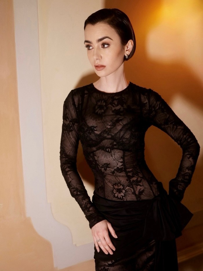 Lily Collins tampil elegan di Venice dengan gaun lace hitam transparan untuk evening press Emily in Paris Season 5. Ia padukan dengan rambut sleek dan makeup bold. /Foto: Instagram/lilyjcollins