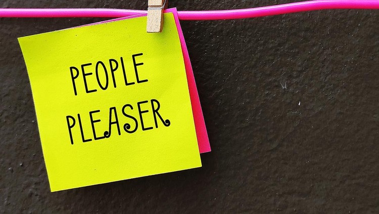 Yellow note clipped with hanger wire with handwritten PEOPLE PLEASER&comma; concept of one who tries hard to make others happy even go out of their way&comma; time or resources&comma;overly concerned with pleasing others