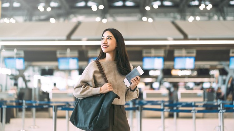 Passenger at international airport terminal for departure with airline transport&period; Portrait of standing tourist woman holding passport and boarding pass to transit&period;