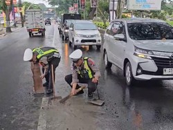 Gercep Personel Satlantas Polres Batu Bersihkan Tumpahan Semen di Jalan