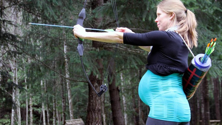 A very pregnant lady archer takes careful aim with her bow and arrow&period;  Concept could be Aim for Success&comma; etc&quest;
