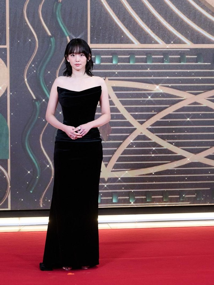 Jin Ki Joo tampil elegan dalam balutan sleeveless dress berwarna hitam, dilengkapi dengan tata rambut bergelombang yang menambah kesan menawan./ Foto: soompi.com