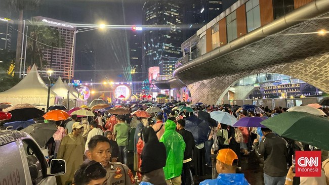 Warga memadati Bundaran HI Jakarta jelang Tahun Baru 2026 meski hujan. Perayaan tanpa kembang api, diisi doa bersama.