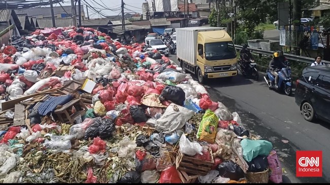 Warga terganggu akibat bau busuk yang menyengat dari gunungan sampah yang menutupi separuh badan jalan di depan Pasar Cimanggis, Ciputat, Tangsel.