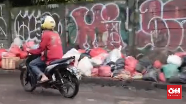 Tumpukan sampah kembali muncul di Pasar Cimanggis, Tangsel. Warga mengeluhkan kurangnya lokasi pembuangan yang memadai. Solusi sementara: buang ke Cileungsi.