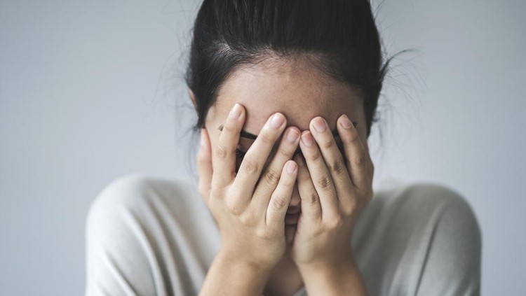 Young girl covering her face with her hands