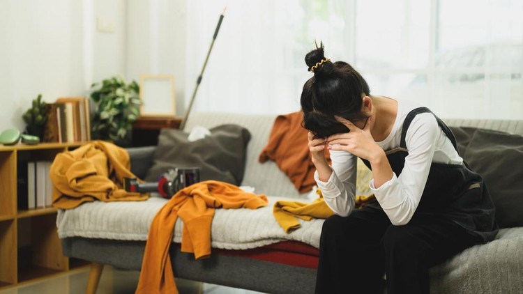 Exhausted woman taking a break during house cleaning in messy living room&period;