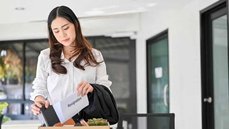 Sad and depressed young Asian female office worker packing her stuff into a cardboard box in the office&comma; quitting her job or getting fired from her boss&period; unemployment&comma; resign&comma; career failure