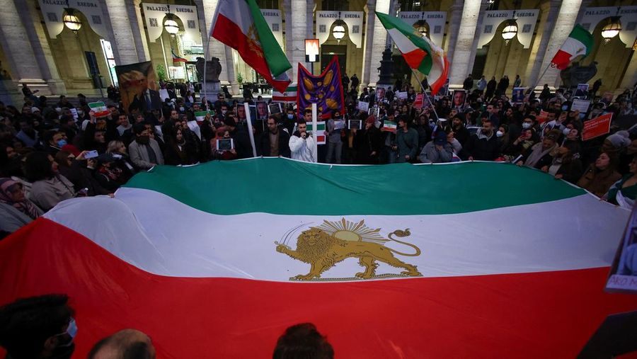Orang-orang memegang bendera nasional "Singa dan Matahari" pra-Revolusi Iran selama unjuk rasa mendukung protes nasional di Iran, di Roma, Italia, 13 Januari 2026. (REUTERS/Francesco Fotia)