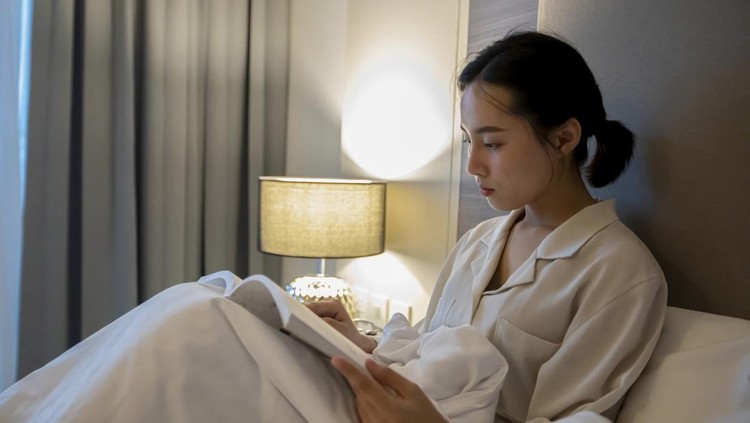 Asian women reading a book and smiling and happy Relaxing in the bedroom at home&comma; she drinking coffee