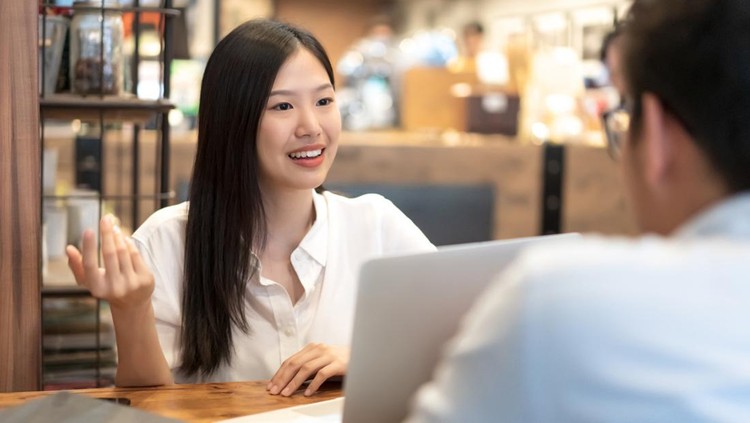 Young Asian woman sitting in cafe talking and having a meeting&period;