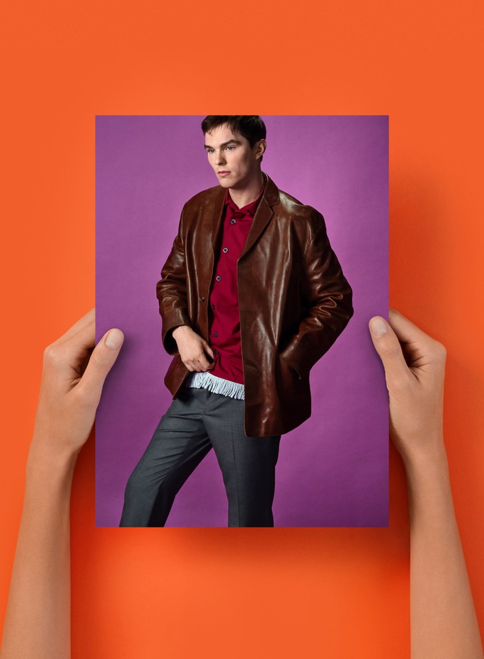 Sama-sama mengenakan aksen merah melalui kemeja, Nicholas Hoult memadukannya dengan leather jacket coklat dan tailored pants abu-abu. / Foto: Dok. Prada/Anne Collier with images by Oliver Hadlee Pearch