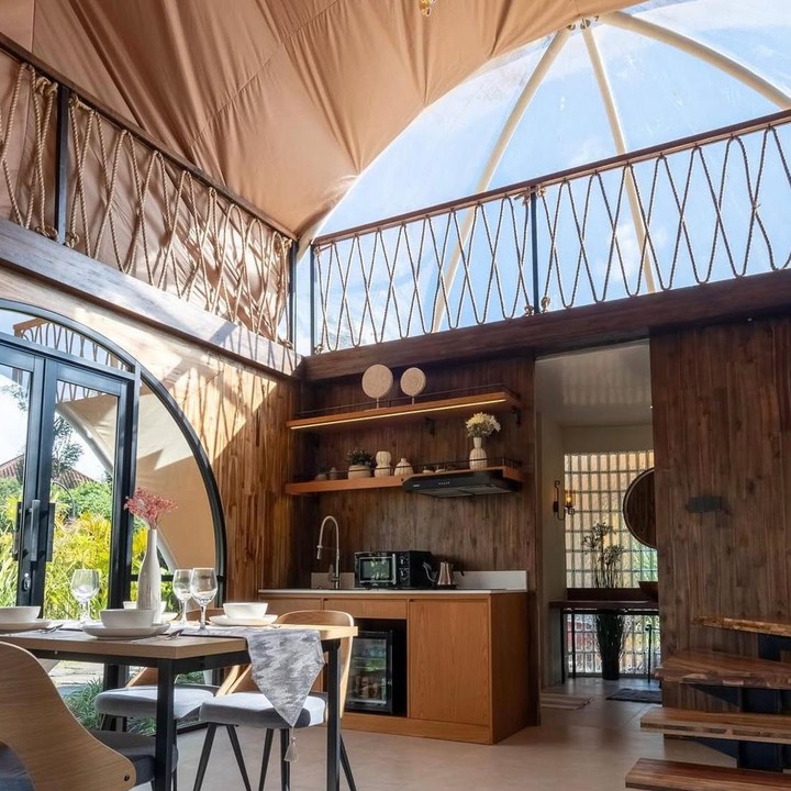 <p>Begitu masuk ke dalam vila, kita langsung disambut dengan <em>mini kitchen </em>dan meja makan dengan desain modern, lengkap dengan plafon yang dibuat tinggi sehingga terasa lebih lapang. Penginapan milik pasangan aktris ini juga didominasi penggunaan kaca di hampir setiap bangunannya. (Foto: Instagram @titi_kamall)</p>