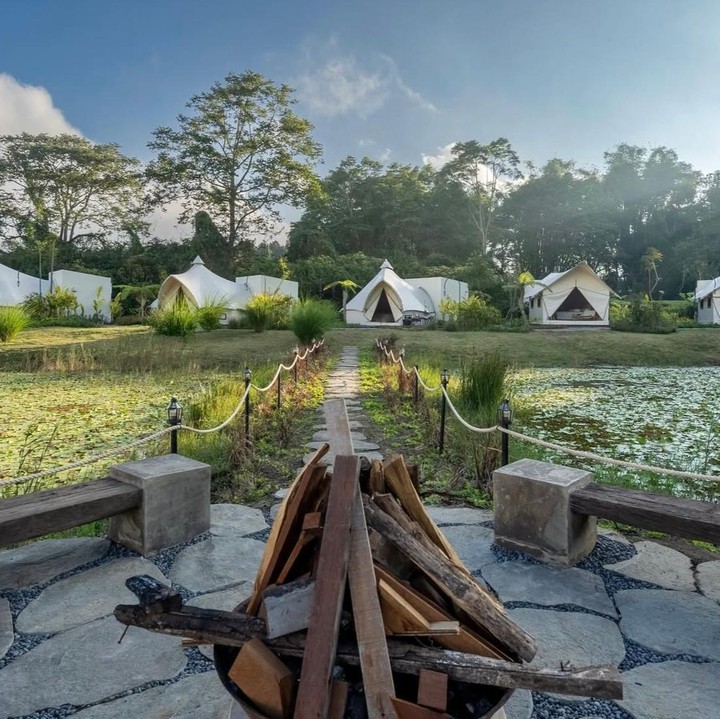 <p>Kalau kita bergeser ke tipe vila dengan konsep <em>camping</em>, kita akan melihat sekelilingnya dipenuhi dengan pepohonan yang menjulang tinggi. Tak kalah menarik, penginapan ini juga dikelilingi perairan yang menambah kesan sejuk dan menenangkan. (Foto: Instagram @titi_kamall)</p>